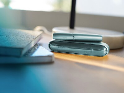 Turquoise IQOS ORIGINALS DUO on a table.